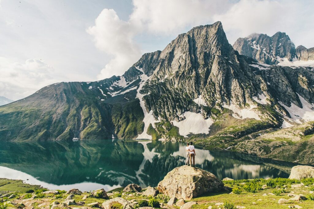 person standing on rock near lake and mountain range