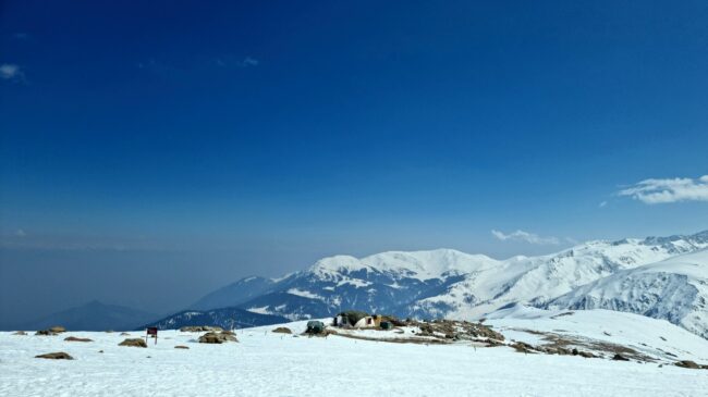 a snow covered mountain with a house on top of it