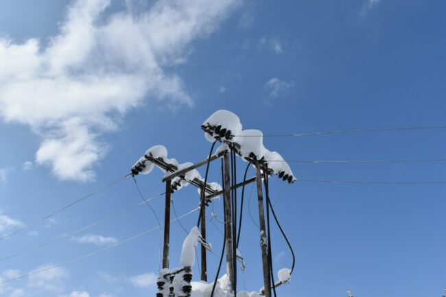 a telephone pole covered in snow under a blue sky